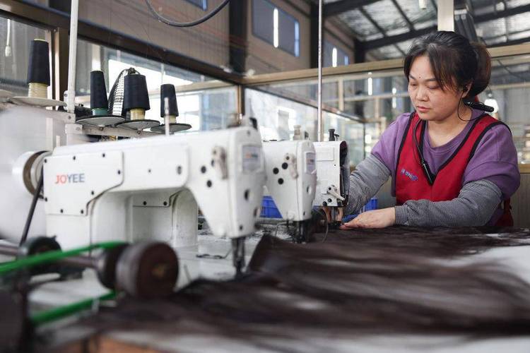5月25日,工人在湖南邵阳美丽来发制品车间内生产假发